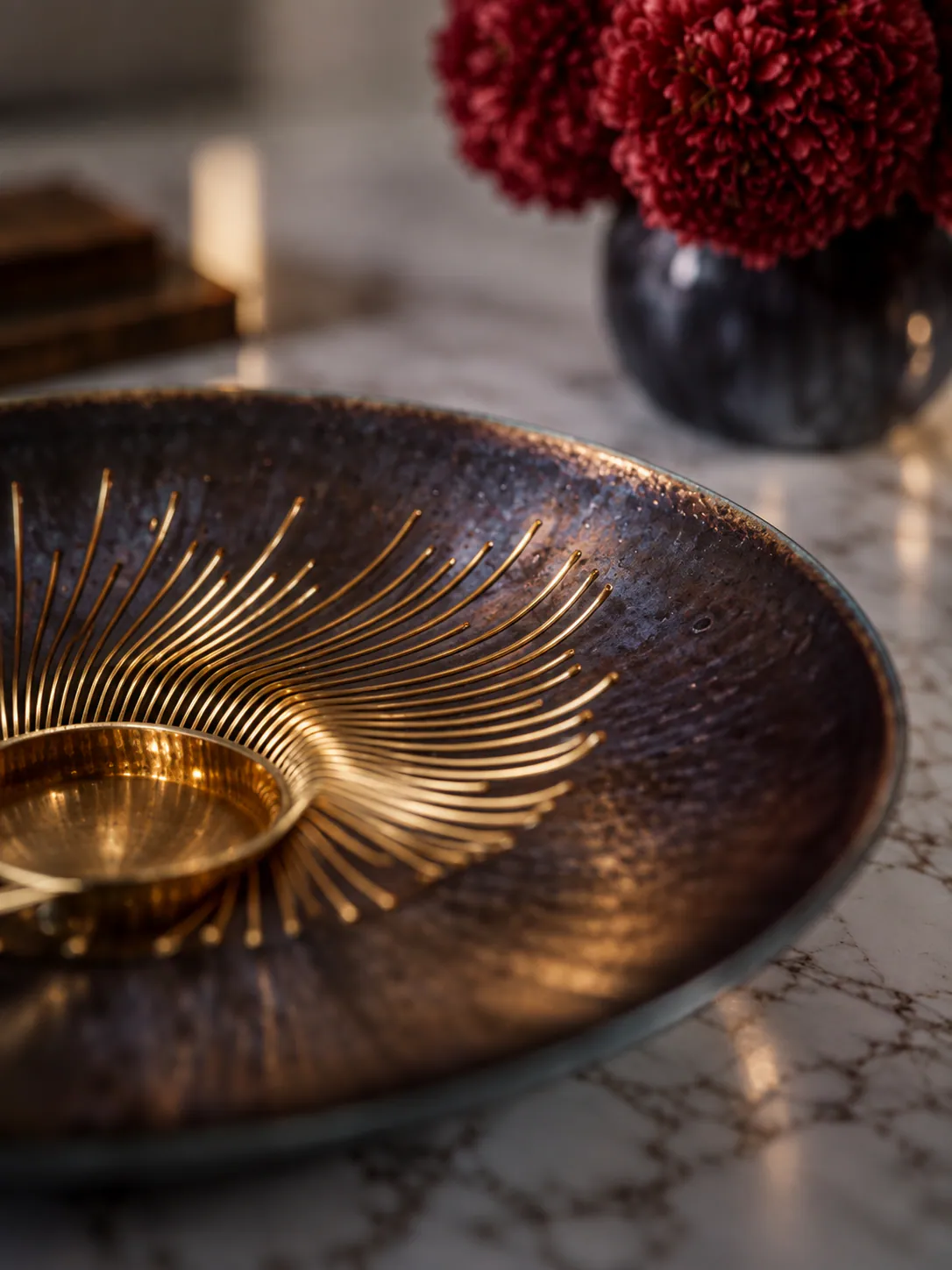 A brass dish with a radiating sunburst pattern on a marble table