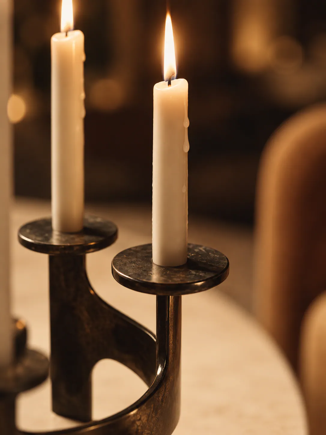 Two candles burning in dark bronze holders, shallow depth of field